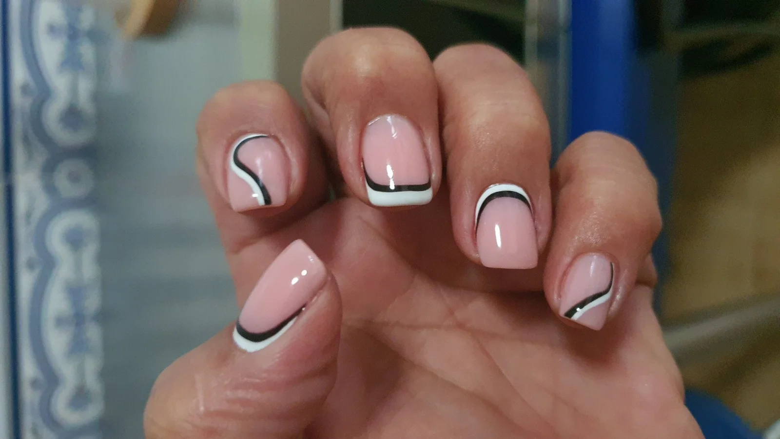 Manicura rosa nude con líneas curvas negras y blancas en estilo francés moderno